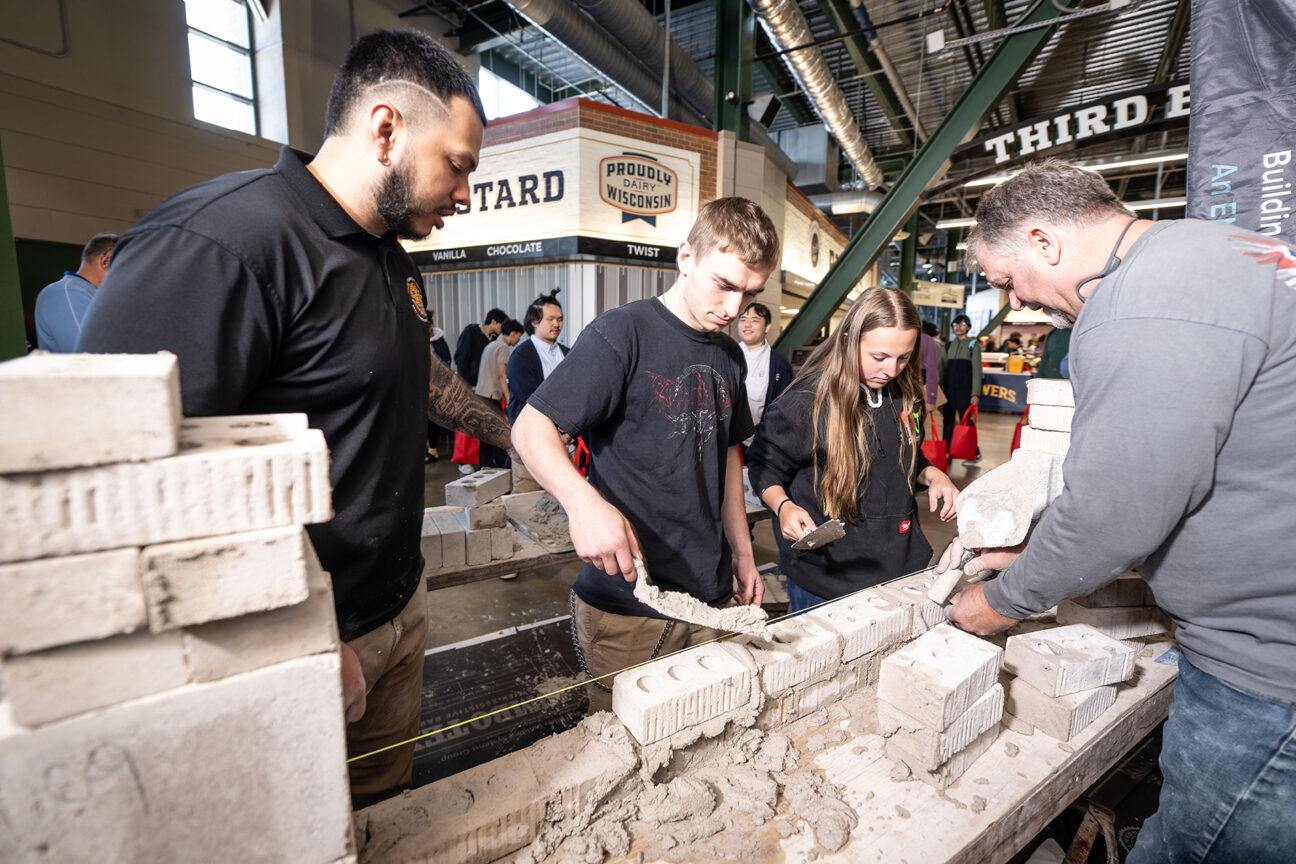 Representing The Bricklayers & Allied Craftworkers District Council of Wisconsin, Jose Luevano (far left) and James Vick (far right) guide West Allis Central High School senior Hawken Boettcher and Brookfield Central High School sophomore Layla Rossa through bricklaying. (Kevin Harnack)